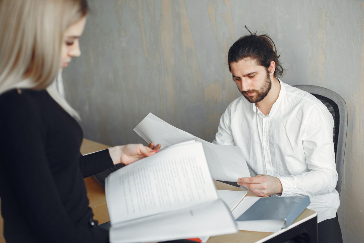 Duas pessoas revisando documentos numa mesa de escritório